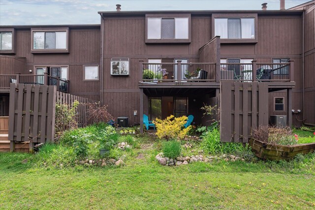 rear view of property featuring a lawn and cooling unit