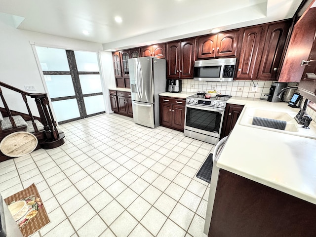 kitchen featuring sink, light tile patterned floors, appliances with stainless steel finishes, backsplash, and a water view