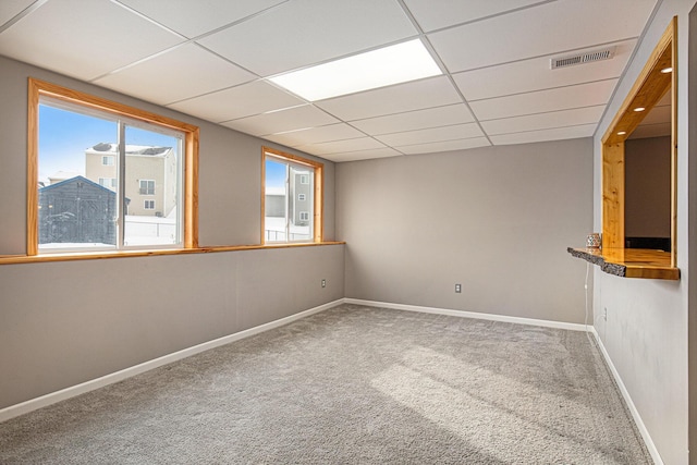 carpeted empty room featuring a paneled ceiling