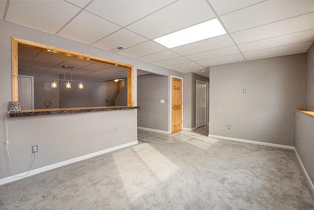 interior space featuring a paneled ceiling and light colored carpet