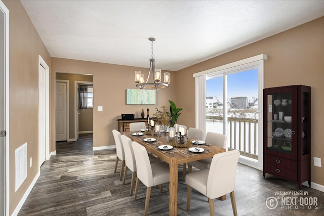 dining room with dark hardwood / wood-style flooring and a chandelier