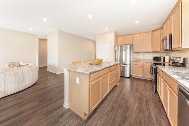 kitchen with a kitchen island, appliances with stainless steel finishes, dark hardwood / wood-style floors, decorative backsplash, and light stone countertops