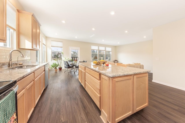 kitchen with sink, light brown cabinets, appliances with stainless steel finishes, a kitchen island, and decorative backsplash