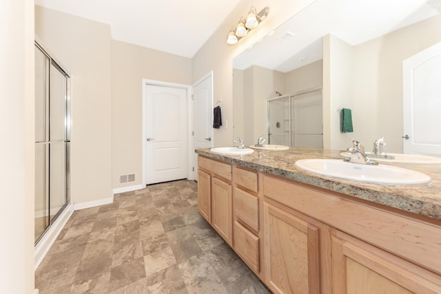 bathroom featuring a shower with door and vanity