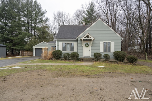 view of front of property with a shingled roof, a chimney, an outdoor structure, and a detached garage