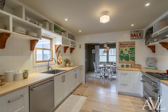 kitchen featuring butcher block countertops, appliances with stainless steel finishes, white cabinetry, open shelves, and a sink