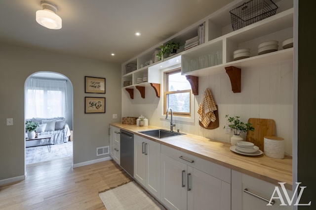 kitchen featuring visible vents, butcher block counters, a sink, open shelves, and stainless steel dishwasher