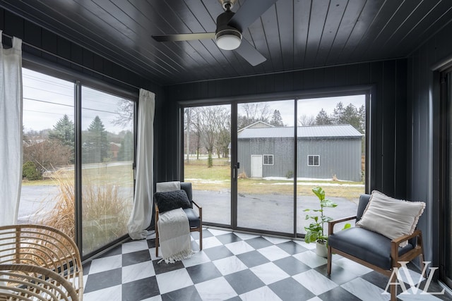 sunroom featuring wood ceiling and a ceiling fan