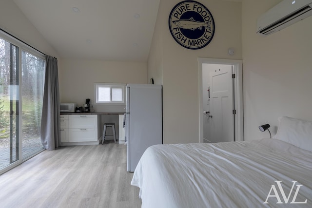 bedroom with light wood finished floors, a wall unit AC, freestanding refrigerator, access to exterior, and vaulted ceiling