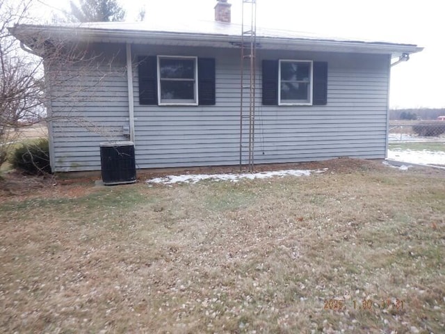 view of side of property with central AC and a yard