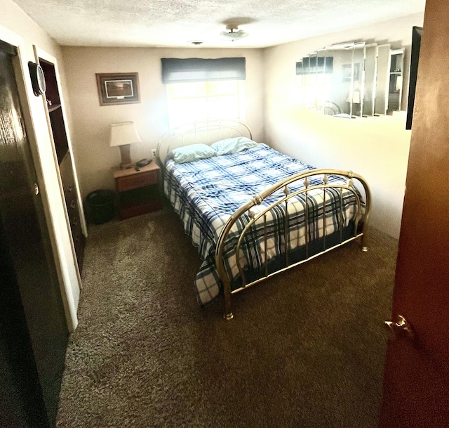 bedroom featuring dark carpet and a textured ceiling