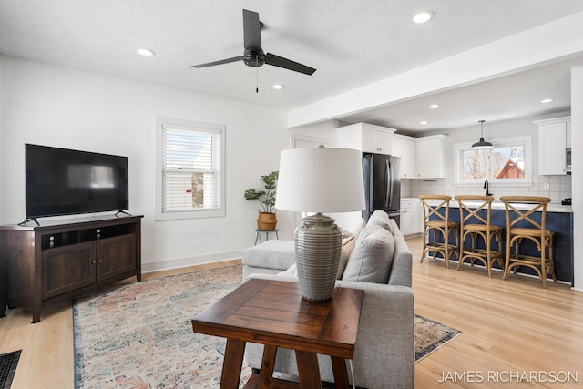 living area with light wood-type flooring, ceiling fan, and recessed lighting