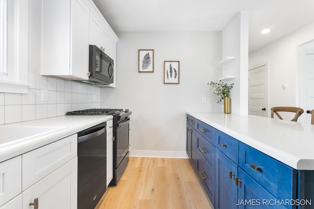 kitchen featuring black appliances, tasteful backsplash, a peninsula, and blue cabinets