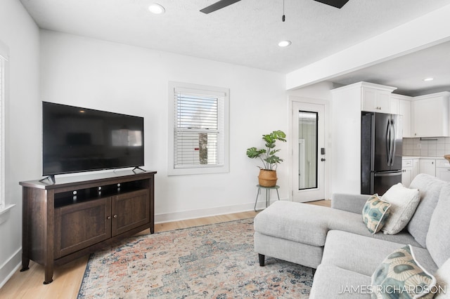 living room with light wood-type flooring, ceiling fan, baseboards, and recessed lighting