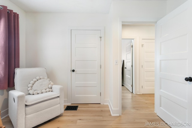 sitting room featuring visible vents, light wood-style flooring, and baseboards