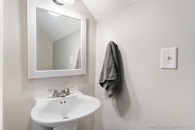 bathroom featuring vaulted ceiling and a sink