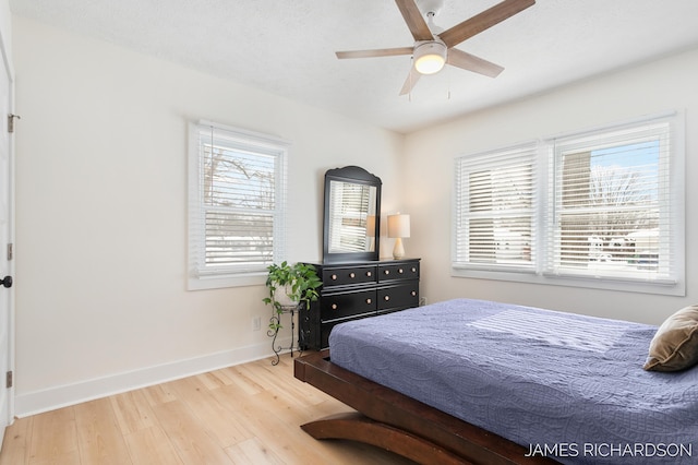 bedroom featuring a ceiling fan, a textured ceiling, baseboards, and wood finished floors