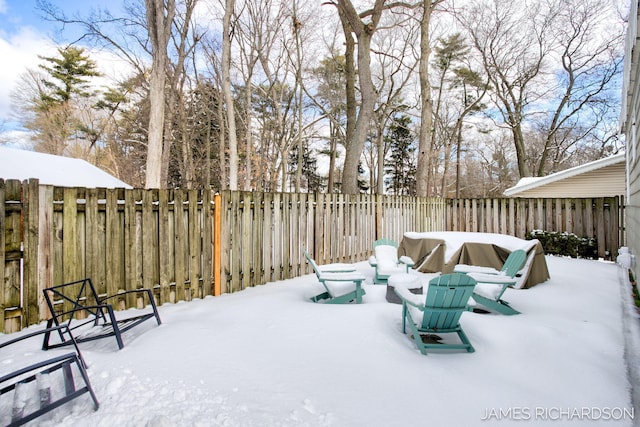 snow covered patio featuring a fenced backyard