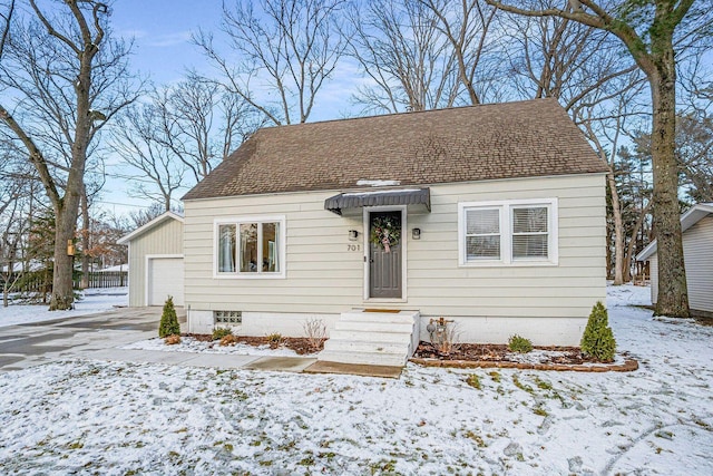 view of front of house featuring a shingled roof, driveway, and a garage