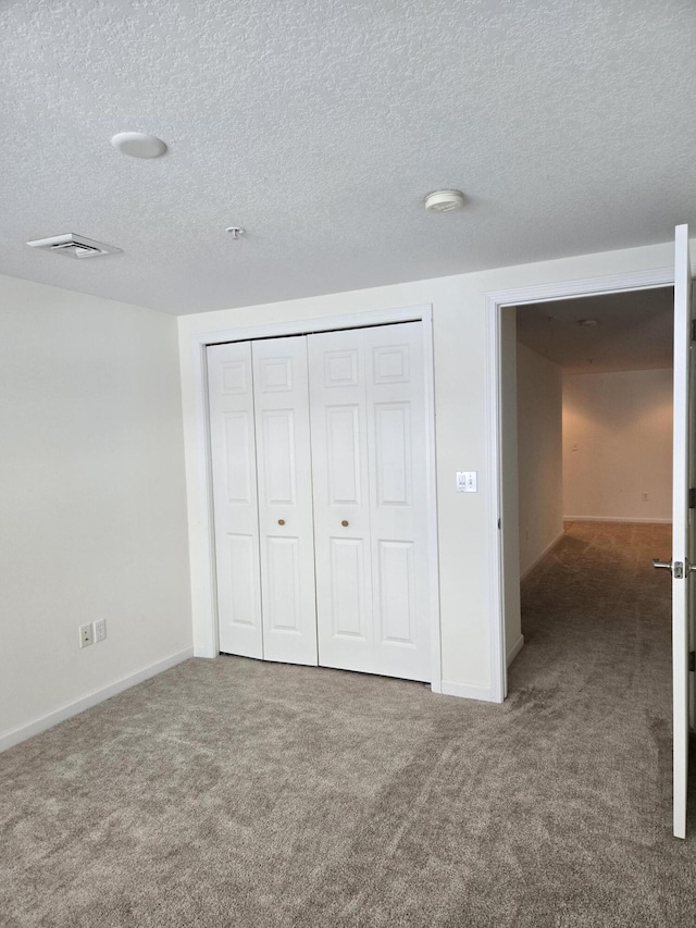 unfurnished bedroom featuring a closet, a textured ceiling, and carpet