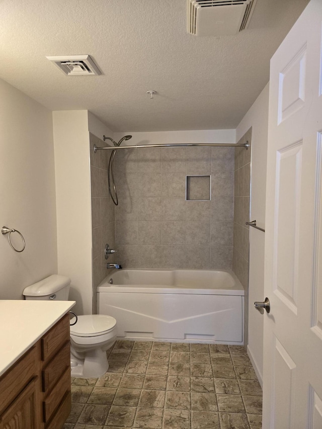 full bathroom with vanity, tiled shower / bath combo, a textured ceiling, and toilet