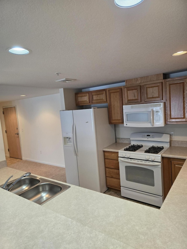 kitchen with sink, white appliances, and a textured ceiling