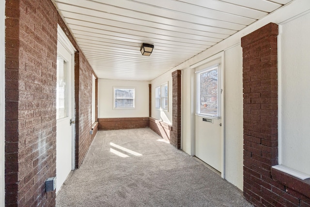 hall with carpet and brick wall