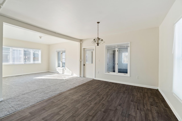 empty room with an inviting chandelier and dark hardwood / wood-style floors