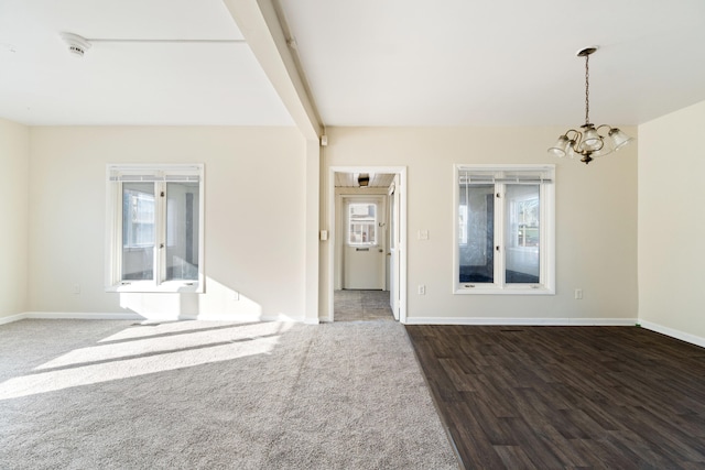 spare room with plenty of natural light, dark hardwood / wood-style floors, an inviting chandelier, and beam ceiling