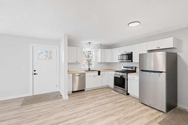 kitchen with appliances with stainless steel finishes, sink, and white cabinets