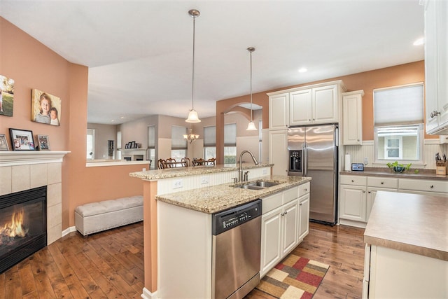 kitchen with a kitchen island with sink, hanging light fixtures, sink, and appliances with stainless steel finishes