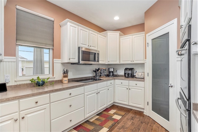 kitchen with dark wood-type flooring, appliances with stainless steel finishes, and white cabinets