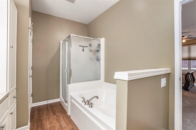 bathroom with plus walk in shower, wood-type flooring, and ceiling fan