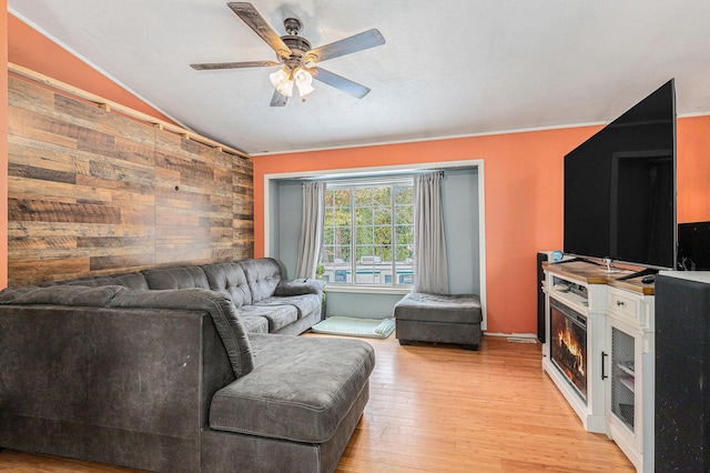 living room featuring lofted ceiling, wood walls, ceiling fan, and light wood-type flooring