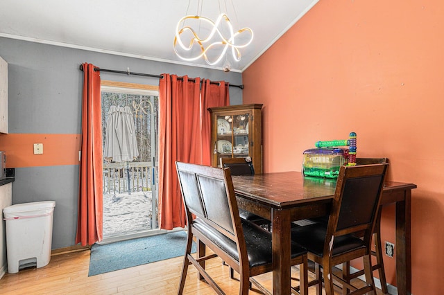 dining area featuring crown molding, vaulted ceiling, a healthy amount of sunlight, and light wood-type flooring