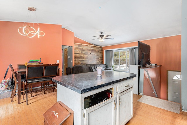 kitchen featuring hanging light fixtures, ceiling fan with notable chandelier, light hardwood / wood-style flooring, and vaulted ceiling