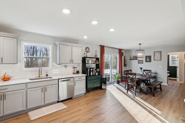 kitchen featuring tasteful backsplash, dishwasher, sink, and light hardwood / wood-style floors