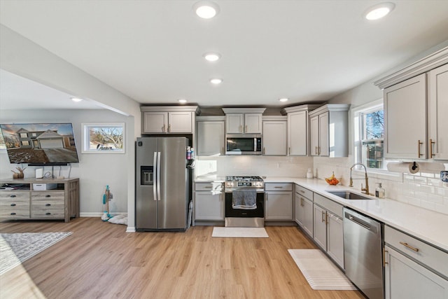 kitchen featuring appliances with stainless steel finishes, sink, gray cabinetry, and light wood-type flooring