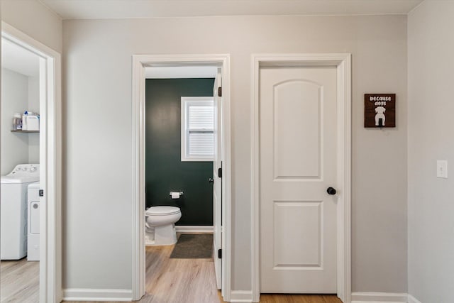 bathroom featuring hardwood / wood-style flooring, washer and clothes dryer, and toilet