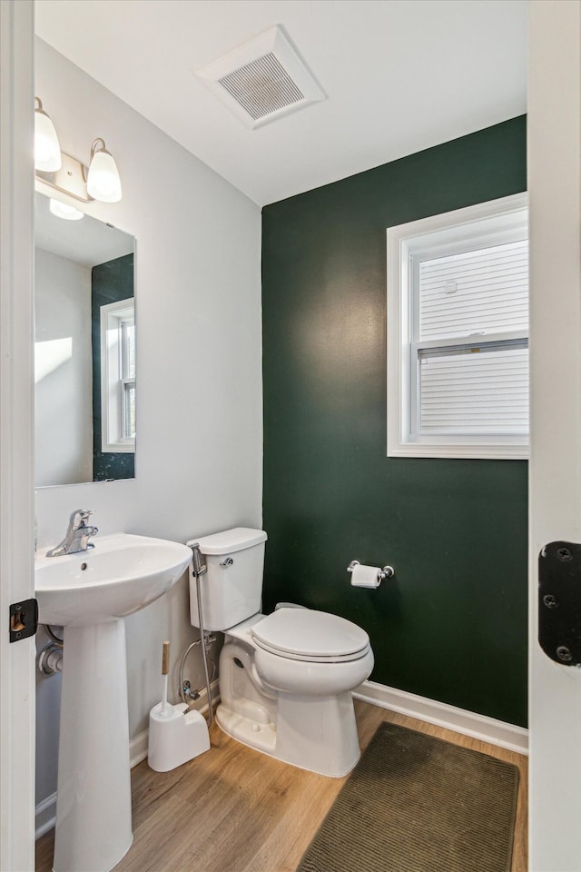 bathroom with hardwood / wood-style flooring, plenty of natural light, toilet, and sink