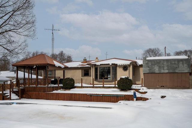 snow covered rear of property featuring a gazebo and a storage shed