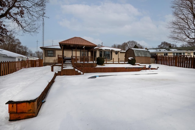 snow covered rear of property featuring a gazebo and a storage shed