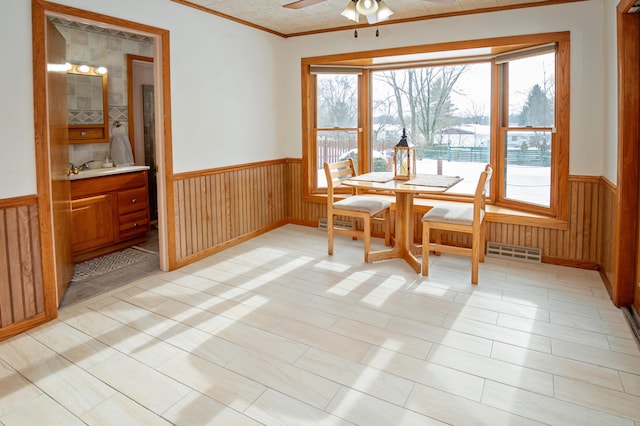 dining area with ceiling fan, wooden walls, and a healthy amount of sunlight