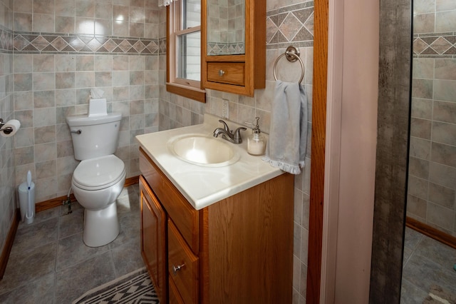 bathroom with vanity, tile patterned floors, toilet, and tile walls