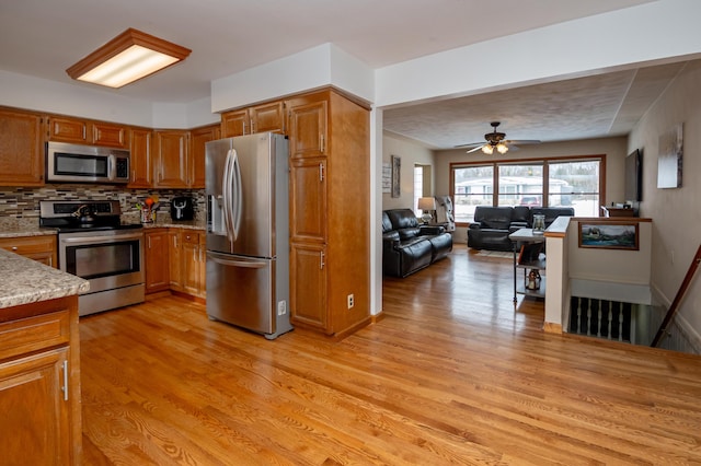 kitchen featuring tasteful backsplash, stainless steel appliances, ceiling fan, and light wood-type flooring