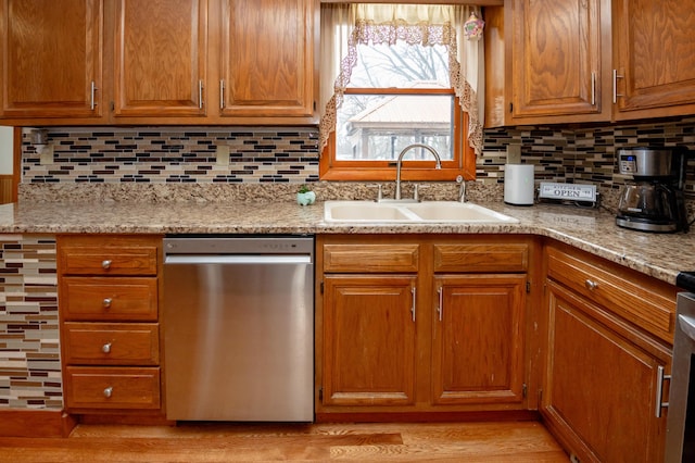 kitchen featuring sink, light hardwood / wood-style flooring, dishwasher, backsplash, and light stone counters