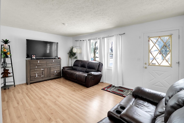 living area with light wood-type flooring, baseboards, and a textured ceiling