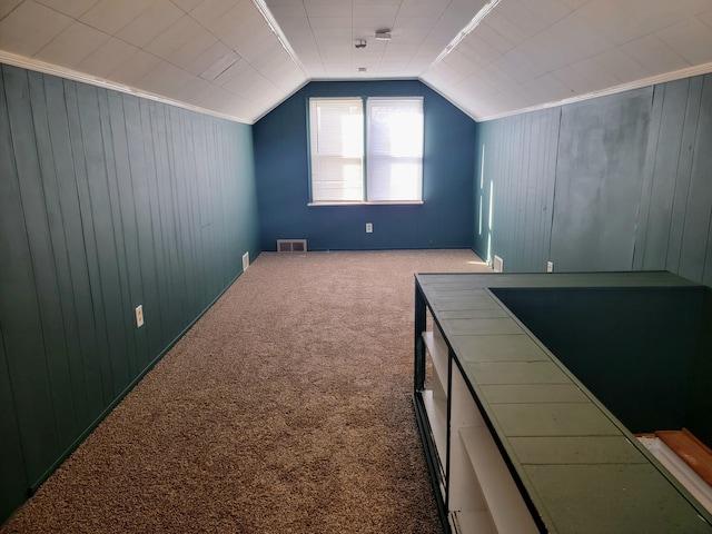 bonus room featuring lofted ceiling, carpet, and wood walls