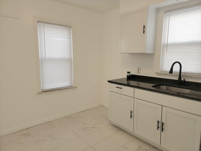 kitchen featuring white cabinetry, sink, and dark stone countertops