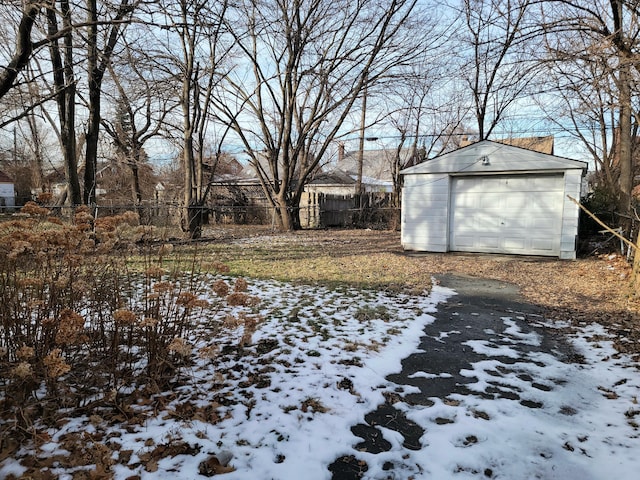 yard layered in snow featuring a garage and an outdoor structure